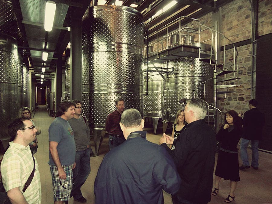 tourists listening to a guide at Domaine Papagiannakos plant in storage tanks area